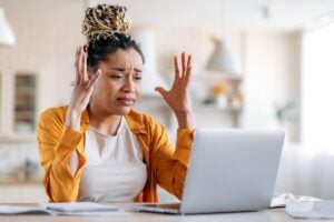 Frustrated woman gesturing with hands at laptop