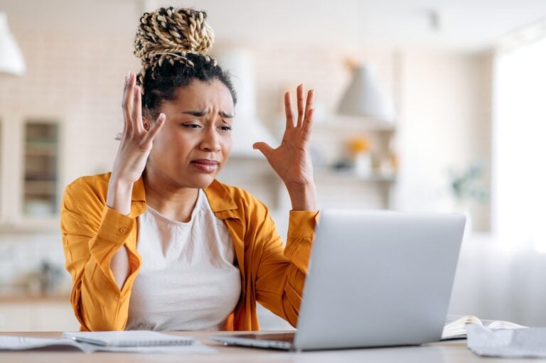 Frustrated woman gesturing with hands at laptop