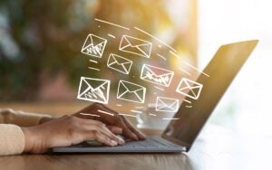 Hands of girl on laptop with email icons floating out of screen